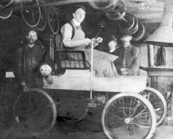 La première voiture à essence construite au Canada serait l’œuvre du Sherbrookois George Foote Foss, qui l’aurait mise au point en 1897. Sur cette photo on voit M. Foss sur sa <em>Fossmobile</em> dans son atelier. Un autre habitant de Sherbrooke, Joseph Fréchette, construit lui aussi une automobile en 1901, et une seconde en 1902.