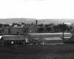 Les premiers bâtiments du complexe industriel de la <em>Rand</em>, à proximité des rues Galt et Belvédère, vers 1901. La rivière Magog et l’usine Paton sont visibles à l’arrière-plan.