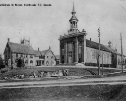 La première cathédrale Saint-Michel sur la rue Marquette, vers 1900. L'église est construite en 1857, et devient la cathédrale de Sherbrooke lors de la création de l'évêché en 1874. Elle est démolie en 1917 pour faire place à la basilique Saint-Michel, dont la construction ne s'achève qu'en 1957.