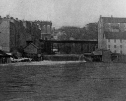 Le site du confluent vers 1898, avec le pont Gilbert-Hyatt et la rue Dufferin. L’usine Sherbrooke Iron Works est située dans le bâtiment blanc à l’avant-plan à droite. Elle y reste jusqu’en 1912.