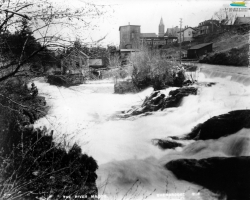 La rivière Magog et la centrale Frontenac (le bâtiment à gauche), vers 1896. Le barrage no 3, hors champs, sert à approvisionner en eau les moulins et manufactures situés à proximité. Il est converti en 1888 pour produire de l’électricité, une source d’énergie adoptée progressivement par les manufactures de Sherbrooke. L’eau sert encore de source d’énergie pendant quelques décennies.