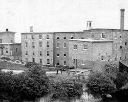Vue de l’arrière des bâtiments de la manufacture de laine d’Adam G. Lomas, située entre la rue Belvédère Nord et la rivière Magog, en 1898.