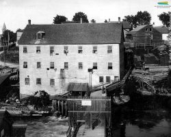 L’arrière de la manufacture de portes et fenêtres de <em>G.G. Bryant & Co.</em>, en 1890. Le bâtiment est situé le long de la rue Belvédère Nord, vis-à-vis du barrage no 2, visible au bas de la photographie.