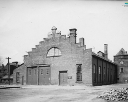 Construit pour l’usine de viande de la <em>Canadian Meat & Produce Company</em> en 1875, le bâtiment est acheté par le <em>Quebec Central railway</em> en 1882. De 1940 à 1946, il servira de camp d’internement pour des ressortissants allemands. Photo: années 1910.