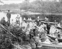 Un groupe de personnes participent à un pique-nique sur les bords de la rivière Saint-François, à proximité de Melbourne, vers 1890. Plusieurs industriels de Sherbrooke organisent chaque année de telles expéditions pour leurs ouvriers.