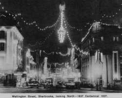 Des photos du centre-ville de Sherbrooke, tout éclairé à l’occasion du « centenaire » de 1937. Les autorités municipales cherchent à stimuler le tourisme et la venue d’industries, entre autres en vantant ses ressources hydroélectriques, et montent de toutes pièces des célébrations du centenaire même si l’année 1937 ne marque le centième anniversaire de rien de significatif,