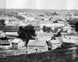 Vue du confluent des rivières Magog et Saint-François depuis le quartier Est, vers 1865. À cette époque l’Est est très peu peuplé, les ouvriers qui y habitent devant marcher une trop longue distance pour aller travailler dans les usines situées dans la gorge de la rivière Magog.