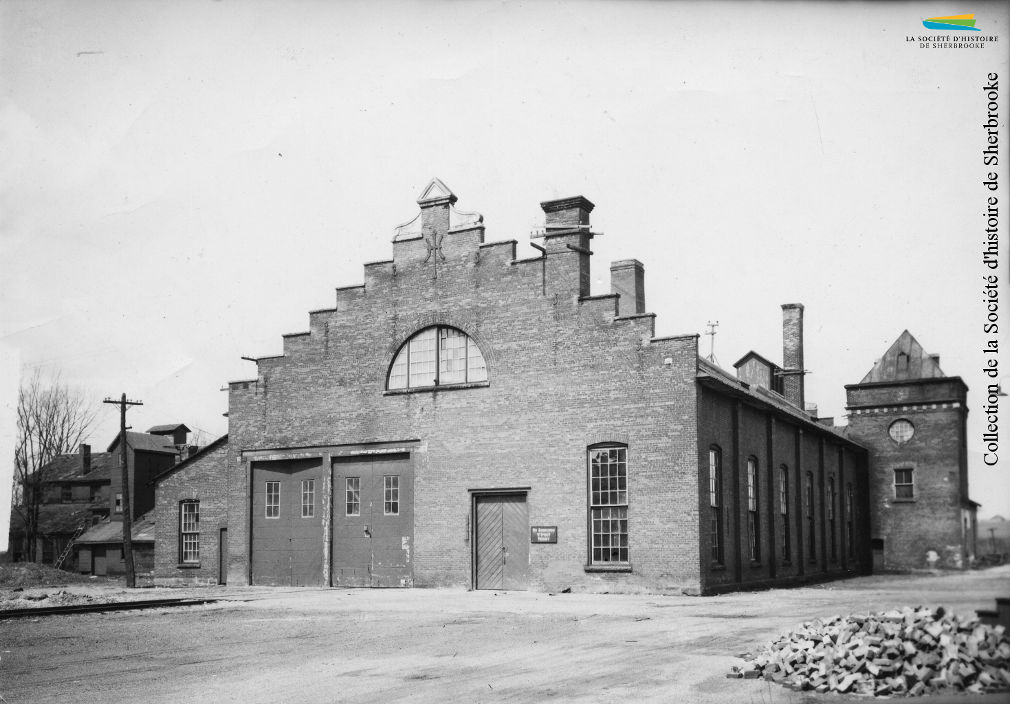 Construit pour l’usine de viande de la <em>Canadian Meat & Produce Company</em> en 1875, le bâtiment est acheté par le <em>Quebec Central railway</em> en 1882. De 1940 à 1946, il servira de camp d’internement pour des ressortissants allemands. Photo: années 1910.