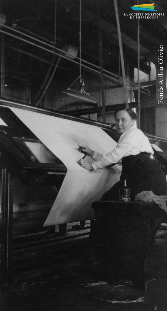 Une femme inspecte une pièce de coton à la Canadian Connecticut Cotton Mills, vers 1928. La majorité de la main-d’œuvre de la plupart des usines de textiles de Sherbrooke est féminine.