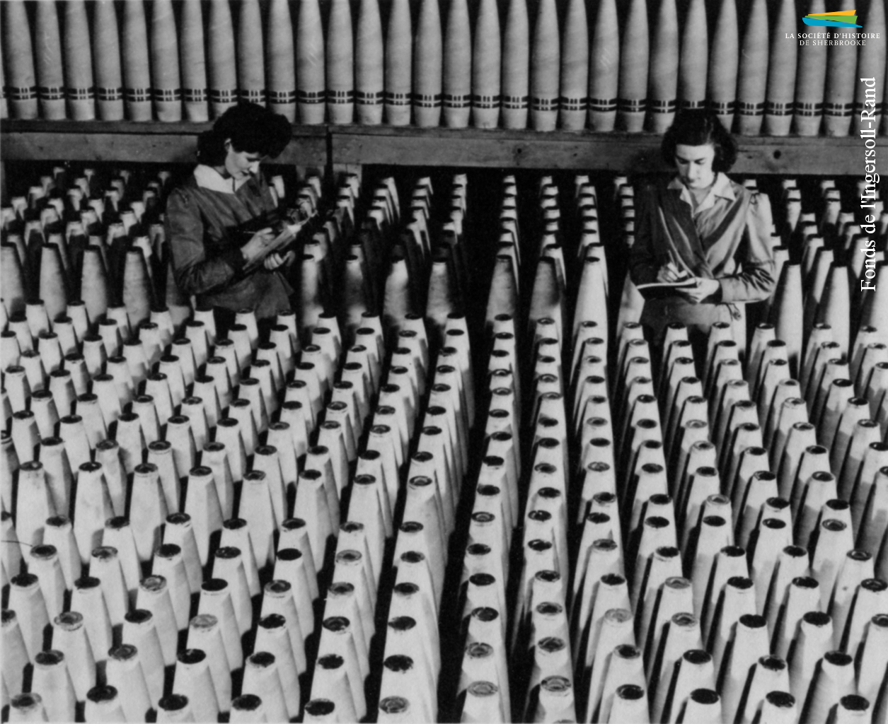 Deux ouvrières de l’Ingersoll-Rand circulent au milieu d’obus, entre 1939 et 1945. L’usine de Sherbrooke reçoit plusieurs commandes de munitions pendant la Seconde Guerre mondiale de la part du gouvernement canadien. Un grand nombre de femmes y sont embauchées.