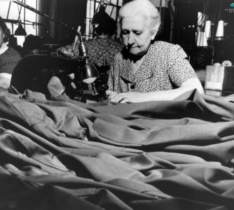 Des femmes travaillent à la confection d’uniformes, pendant la Seconde Guerre mondiale (1939-1945). À Sherbrooke, les manufactures de tissus (Paton, Dominion Textile) et de vêtements (S. Rubin Ltd) reçoivent de telles commandes du gouvernement canadien.
