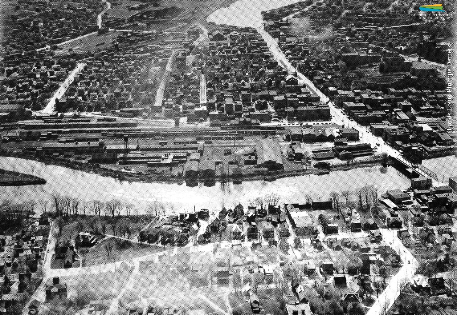 Une vue aérienne du quartier Centre et de la rue King depuis l’est de Sherbrooke, vers 1950. Au centre se trouve le complexe industriel construit par la <em>Jenckes Machine Co.</em> en 1894, et tout autour des habitations.