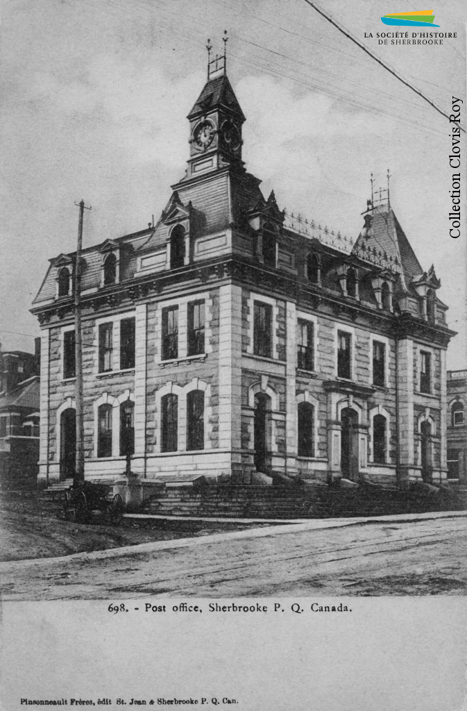 Le bureau de poste de Sherbrooke, vers 1905. Construit en 1885, il garde cette fonction jusqu’en 1953 et devient alors la bibliothèque municipale. Au moment de sa construction, le courrier est transporté par train, mais avant l’arrivée du chemin de fer ce sont des diligences qui assurent ce service à partir de Québec ou de Boston.