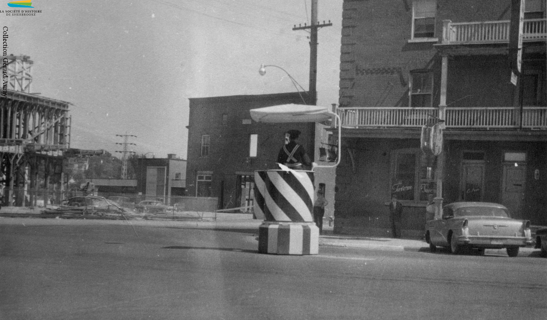 Un policier dirige la circulation au coin des rues King Ouest et Grandes-Fourches, vers 1957. Malgré la présence de feux de circulation depuis 1930, ces policiers restent présents sur certains carrefours routiers de Sherbrooke jusque dans les années 1970.