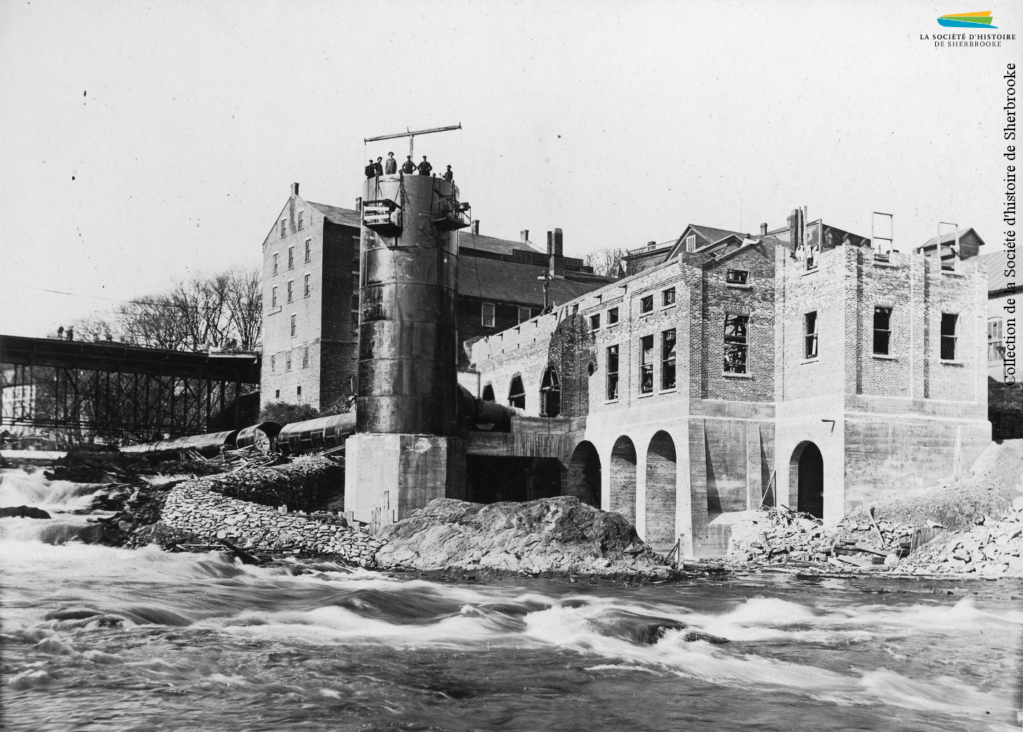 Construction de la centrale hydroélectrique de la compagnie de tramway Sherbrooke Railway & Power en 1911. La centrale est alimentée en eau par le barrage no 4, reconstruit lui aussi, et dont l’eau est acheminée par une longue conduite d’amenée. Cette centrale est aujourd’hui la centrale Abénaquis.